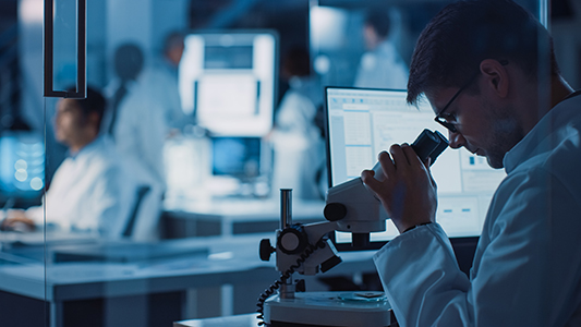 a man looking into a microscope in a lab