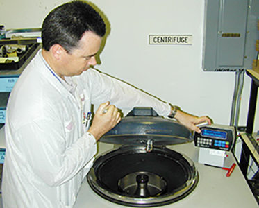 A man operating a laboratory centrifuge.