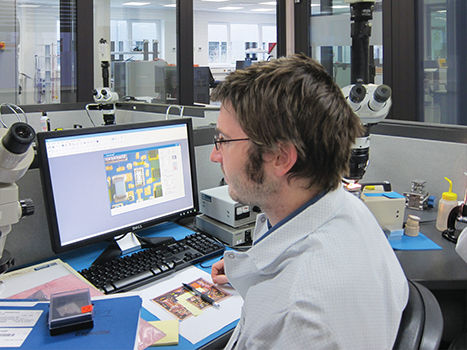 Man examining circuit board under microscope.